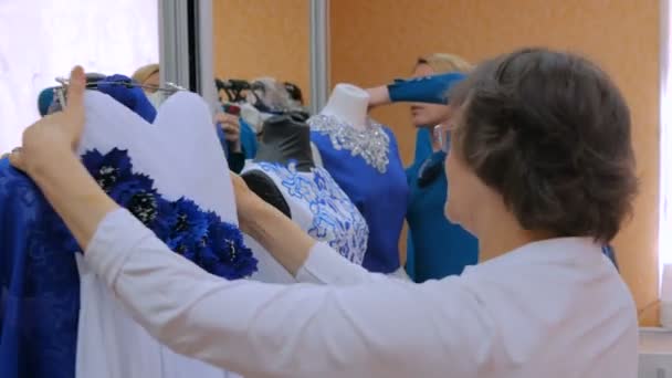 Twee mode-ontwerpers werken met nieuwe model op maat jurk op etalagepop — Stockvideo