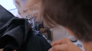 Profesyonel terzi, moda tasarımcısı dikiş makinesiyle elbise dikiyor.