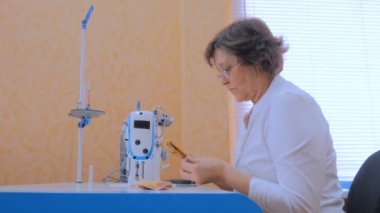 Profesyonel terzi, moda tasarımcısı dikiş makinesiyle elbise dikiyor.