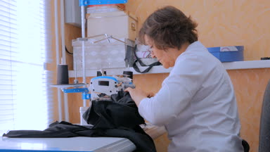 Profesyonel terzi, moda tasarımcısı dikiş makinesiyle elbise dikiyor.