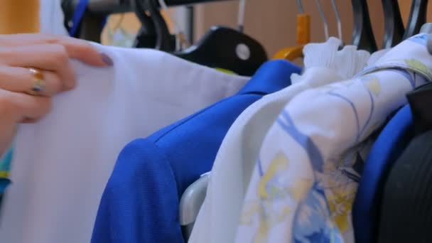 Vrouw handen soorten uit hanger met kleding — Stockvideo