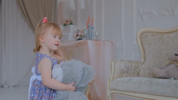 Portrait de drôle de petite fille avec poupée ours à la maison — Video