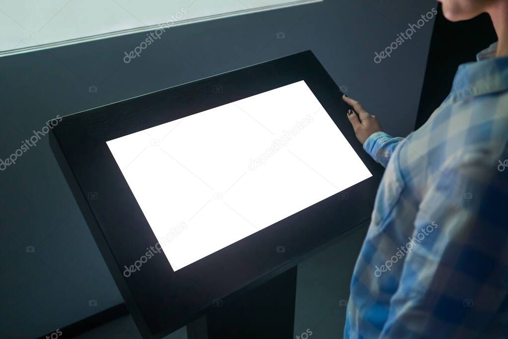 Woman using interactive white empty touchscreen display kiosk at exhibition