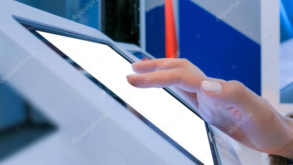 Close up view: woman using floor standing tablet kiosk with blank white display