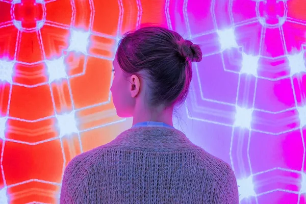 Genç bir kadın modern sanatsal sergiye bakıyor.