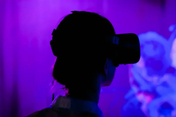 Jovem usando fones de ouvido de realidade virtual em exposição interativa escura — Fotografia de Stock