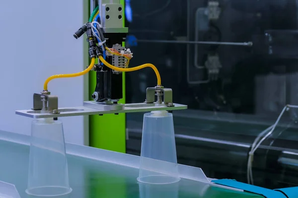 Lini produksi robot otomatis dengan cangkir plastik bergerak pada sabuk konveyor — Stok Foto
