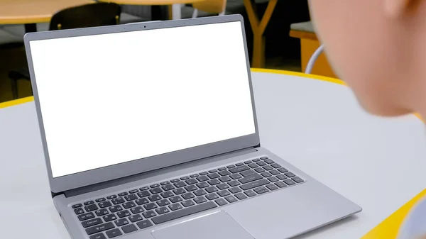 Grey laptop with white blank screen on table in cafe interior