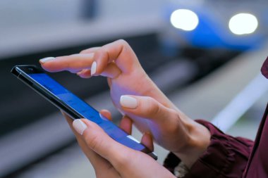 Metro istasyonunda akıllı telefon kullanan bir kadın.