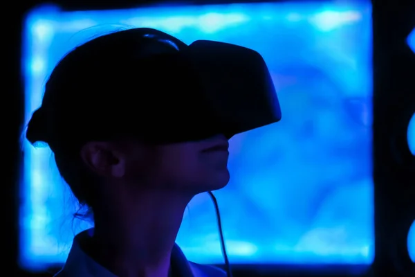 Young woman using virtual reality headset at dark interactive exhibition