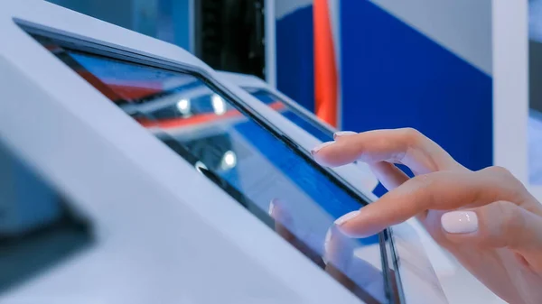Frauenhand mit Touchscreen-Display am bodenstehenden weißen Tablet-Kiosk Stockbild