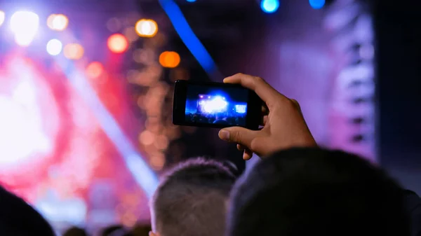 Man hands silhouette recording video of live music concert with smartphone