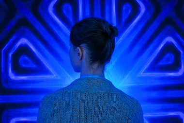 Genç bir kadın modern sanatsal sergiye bakıyor.