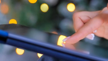 Görüntüyü kapat - dokunmatik ekran tableti kullanan kadın, Noel ışığı arka planı