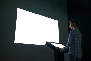 Woman looking at white empty large wall display - mockup image