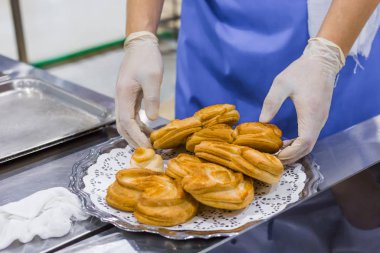 Fırıncı elleri tabağa taze kalp şeklinde çörekler koyar - profesyonel yemek pişirme konsepti