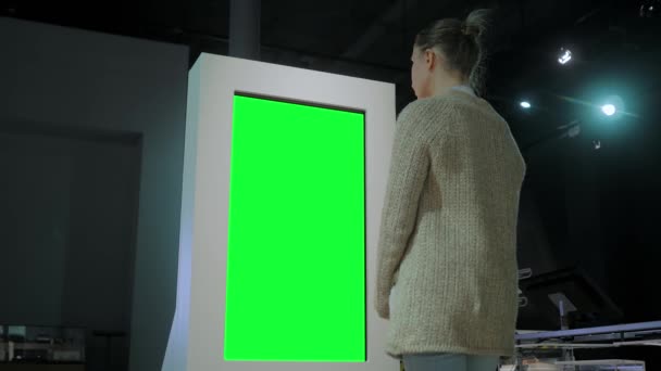 Concepto de pantalla verde - mujer mirando en blanco quiosco pantalla verde en la exposición — Vídeos de Stock