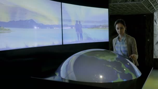 Женщина с помощью интерактивной модели Земли в музее — стоковое видео