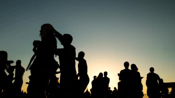 Люди силуети вчаться танцювати на міській набережній під час заходу сонця - повільно. — стокове відео