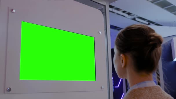 Koncept zelené obrazovky - žena hledící na prázdnou zelenou zobrazovací zeď na výstavě — Stock video