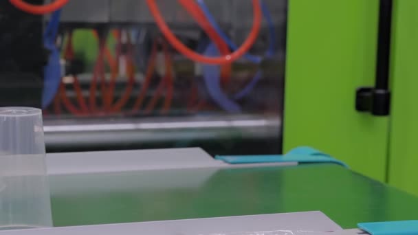 Kubki na taśmie przenośnika z wtryskarki z tworzywa sztucznego z ramieniem robota — Wideo stockowe