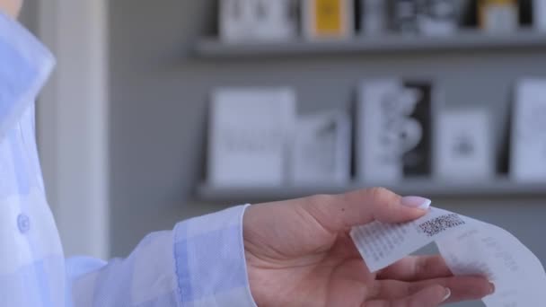 Close up: woman using smartphone and scanning qr code on cash shop receipt paper — Stock Video