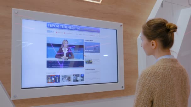 Mulher assistindo TV notícias na parede de exibição interativa — Vídeo de Stock