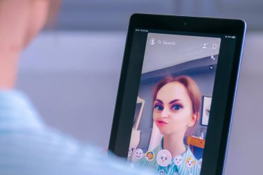 Tablette yüz maskesi olan Snapchat multimedya mesajlaşma uygulamasını kullanan kadın