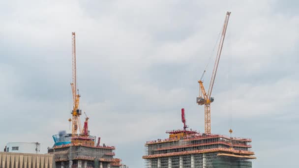 Zeitraffer beweglicher gelber Turmdrehkräne und unvollendeter Hochbau — Stockvideo