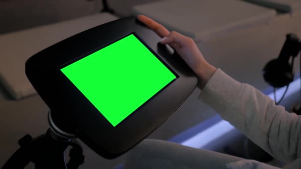 Woman looking at floor standing black tablet kiosk with blank green display — Stock Video