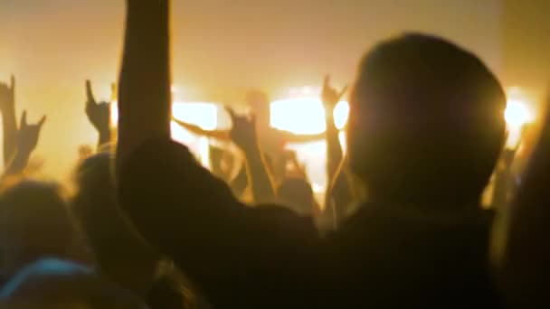 Powolny ruch: sylwetki osób imprezujących na koncercie rockowym przed sceną — Wideo stockowe