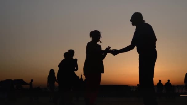 Люди силуети вчаться танцювати на набережній під час заходу сонця - супер повільний рух — стокове відео