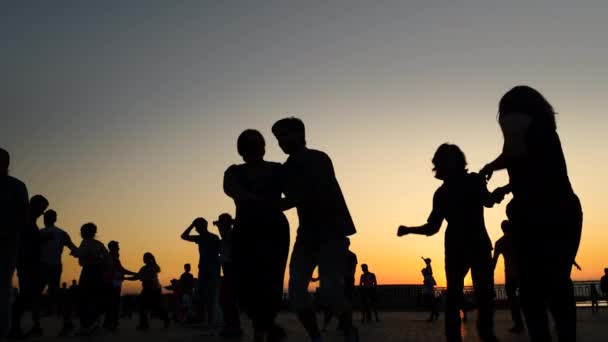 Az emberek sziluettek megtanulják, hogyan kell táncolni a város rakparton naplementekor - lassított felvétel — Stock videók
