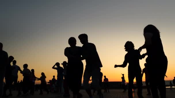 Siluetas de la gente aprendiendo a bailar en el muelle de la ciudad al atardecer - cámara lenta — Vídeo de stock