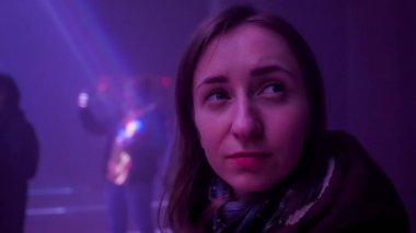 Genç bir kadın etrafına bakıyor ve karanlık odada parlak bir lazer gösterisine hayran: