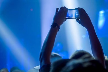 Adam akıllı telefonlu canlı müzik konseri videosu kaydediyor.