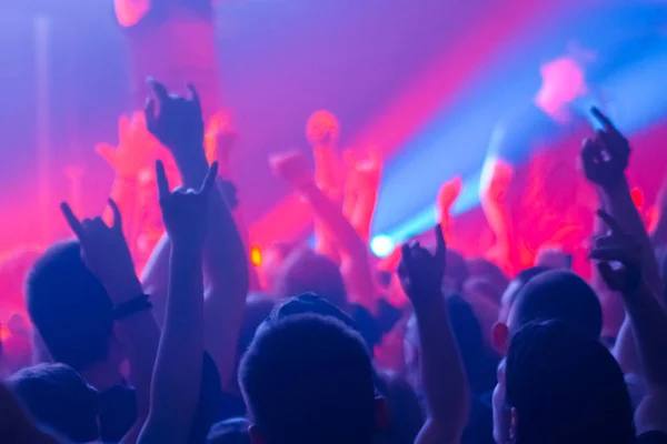 People partying and jumping at rock concert in front of stage of nightclub