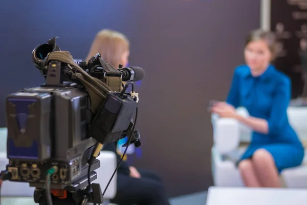 Television video camera recording interview in broadcast news studio