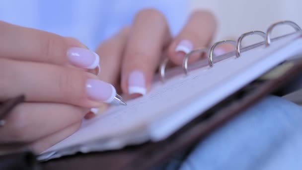 Frau hält Stift in der Hand und schreibt Aufgabenliste in Notizbuch — Stockvideo