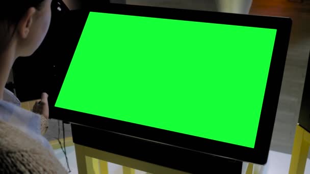 Зеленый экран концепции - женщина смотрит на пустой интерактивный зеленый киоск дисплея — стоковое видео
