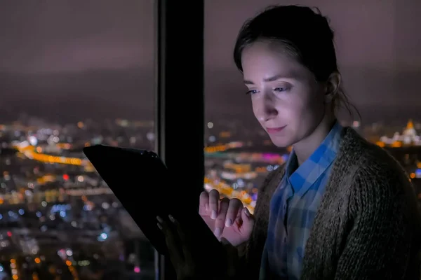 Woman using black digital tablet at night