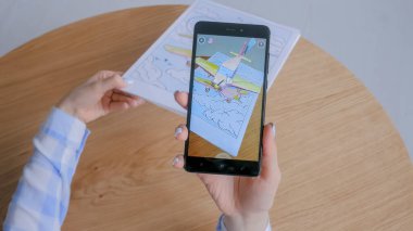 AR uygulamalı akıllı telefon kullanan bir kadın - uçan tek kanatlı uçağın sanal modeli