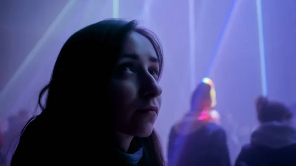 Vista de perto: mulher olhando ao redor e admirando o show de laser brilhante no quarto escuro — Fotografia de Stock
