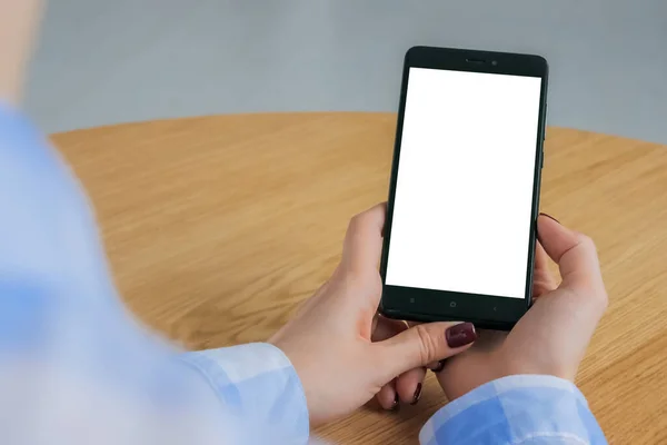 Woman holding black smartphone with white blank screen - mockup image