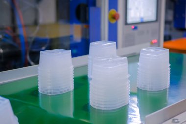 Plastik enjeksiyon makinesinin taşıyıcı bandında yiyecek kapları yığını