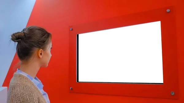 White screen concept - woman looking at blank white display wall at exhibition