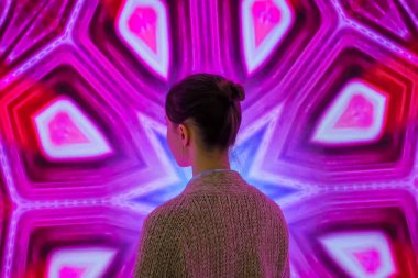 Genç bir kadın modern sanatsal sergiye bakıyor.