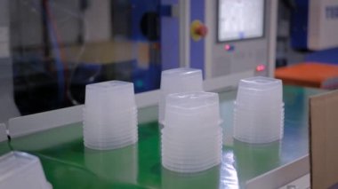 Taşıma bandında plastik gıda kapları olan otomatik robot üretim hattı