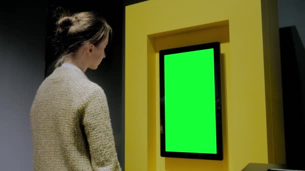 Mujer mirando la pared de visualización verde en blanco en la exposición - concepto de pantalla verde — Vídeo de stock