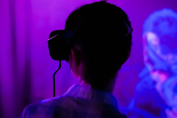 Jovem usando fones de ouvido de realidade virtual em exposição interativa escura — Fotografia de Stock